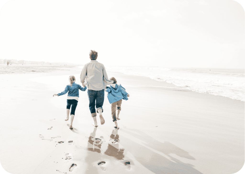 Dad running along the beach with his kids